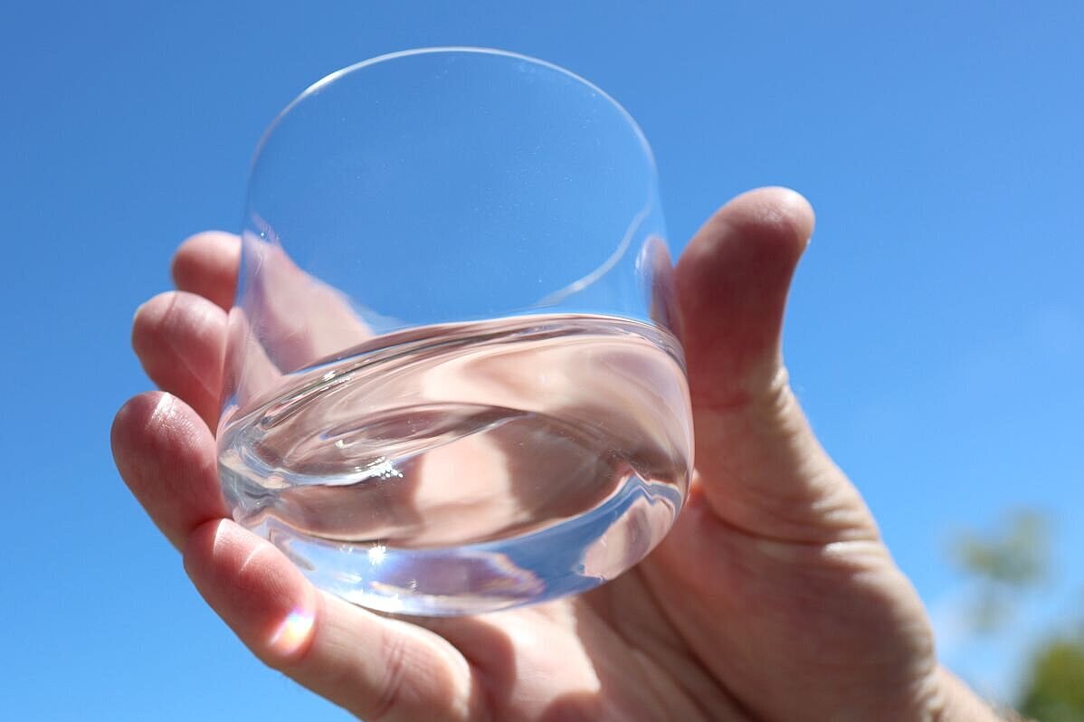Hand hält Wasserglas