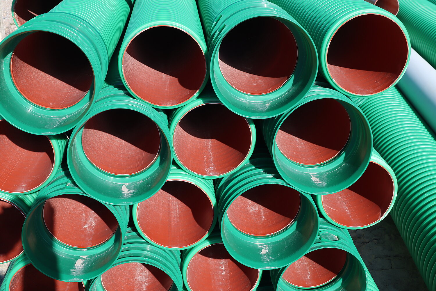 Grüne Rohre liegen gestapelt übereinander.
