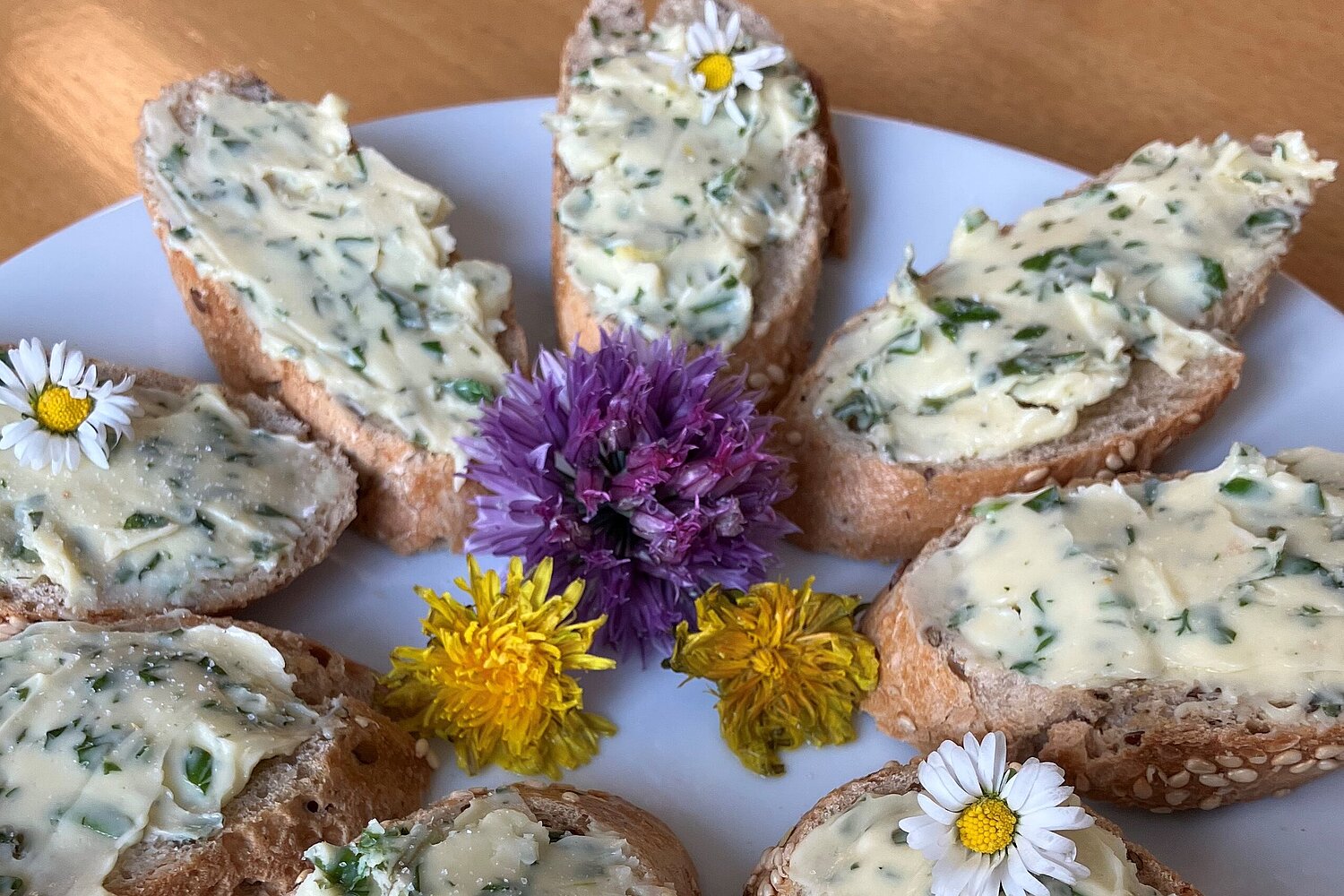 Brötchen mit Kräuterbutter, kreisförmig auf einem Teller präsentiert.