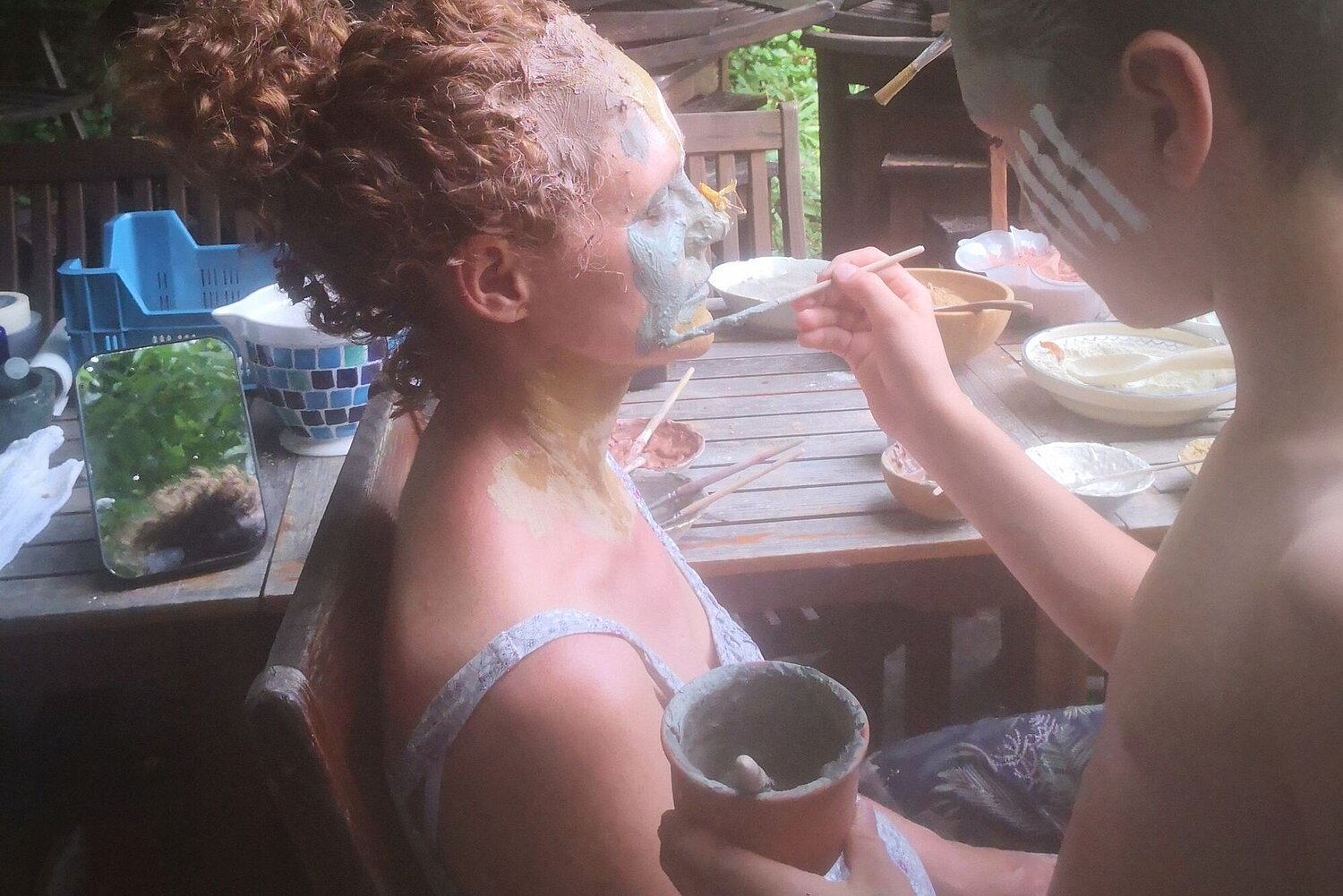 Ein Kind bemalt seine Mama mit Bodenfarbe