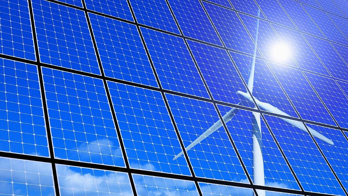 Spiegelung der Sonne und eines Windrads in einem Solarpanel