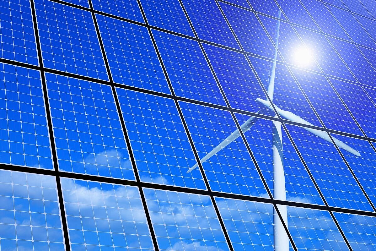 Spiegelung der Sonne und eines Windrads in einem Solarpanel
