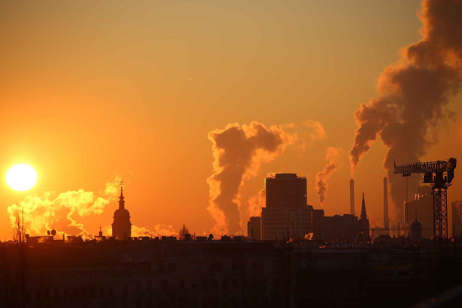 Sonnenaufgang in einer Landschaft mit rauchenden Schloten