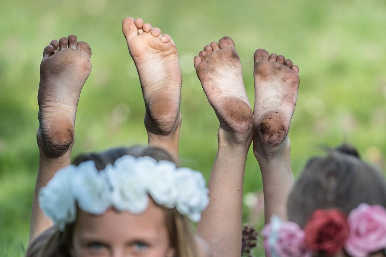 Mädchen in der Blumenwiese mit gatschigen Füssen