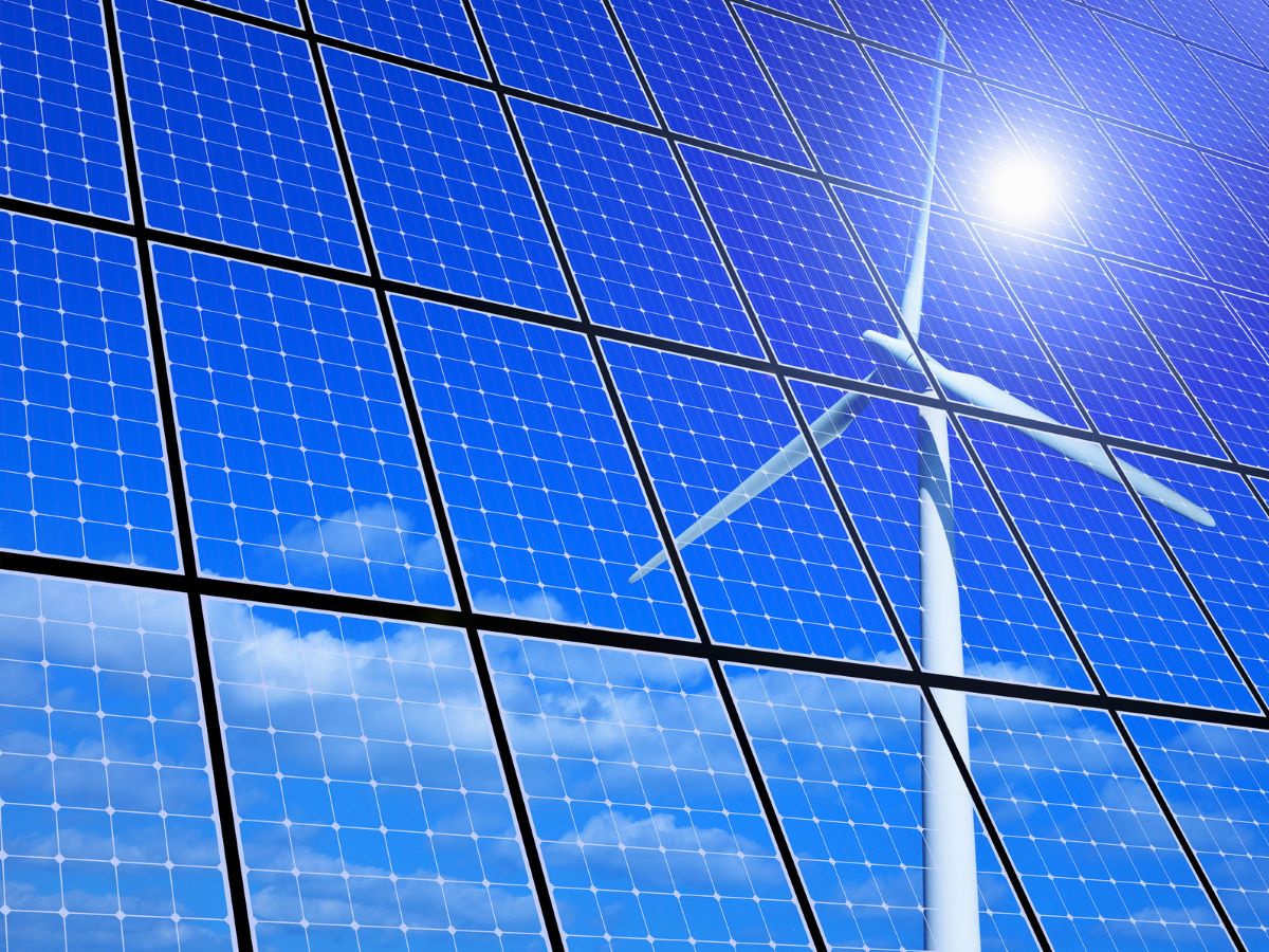 Spiegelung der Sonne und eines Windrads in einem Solarpanel