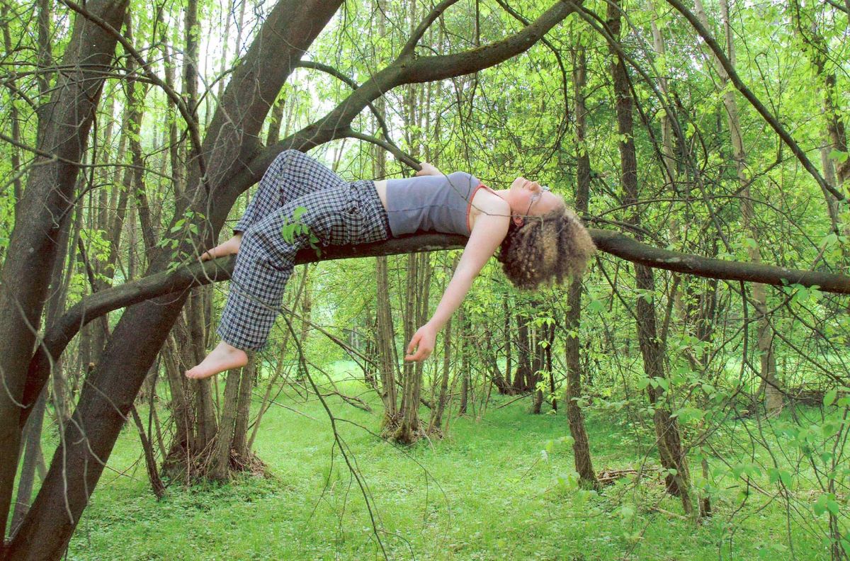 Frau liegt auf dem Ast eines Baumes im Wald