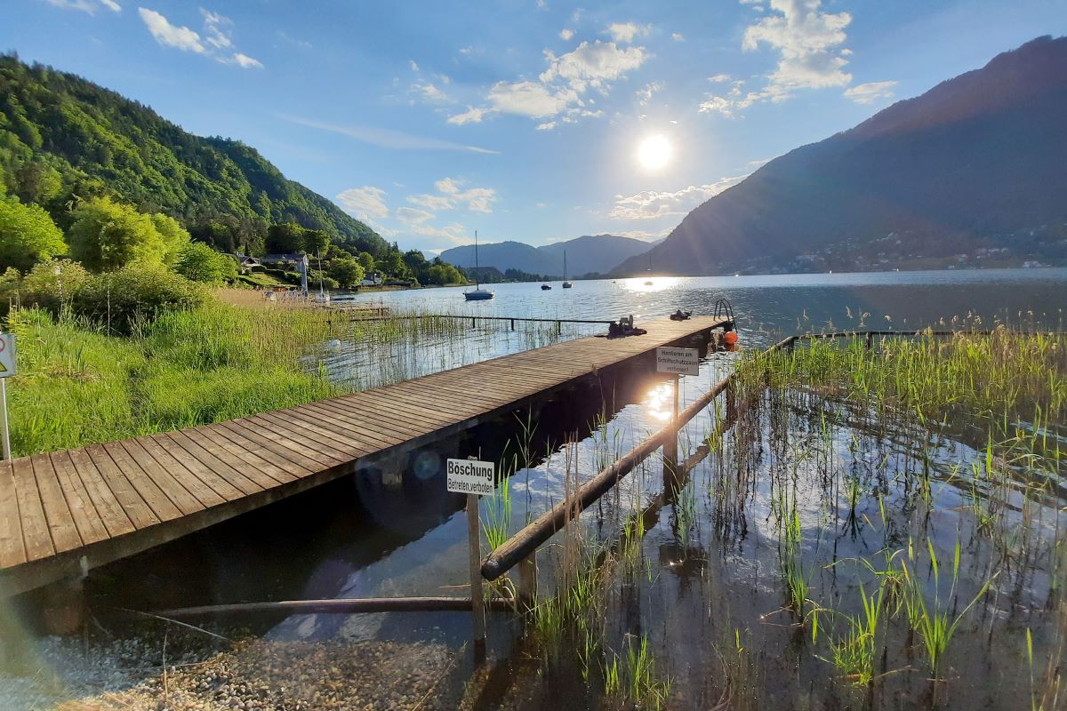 Steg in einen See, im Hintergrund Berge