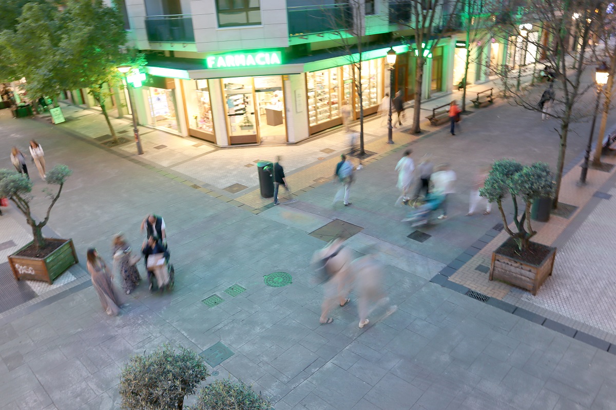 Personen flanieren auf Fussgängerzone in der Dämmerung.