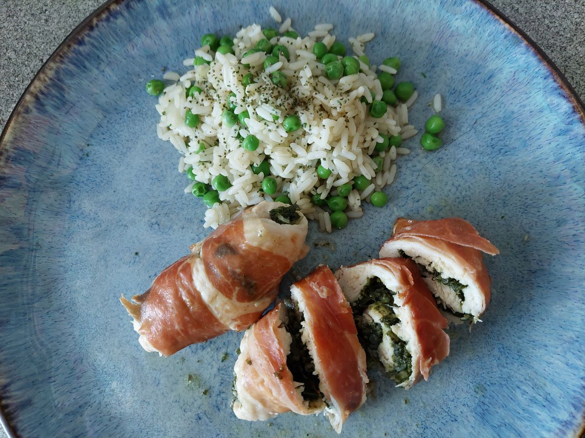 Mehrere Hühnchenroladen-Stücke auf einem blauen Teller mit einer Portion Reis als Beilage.